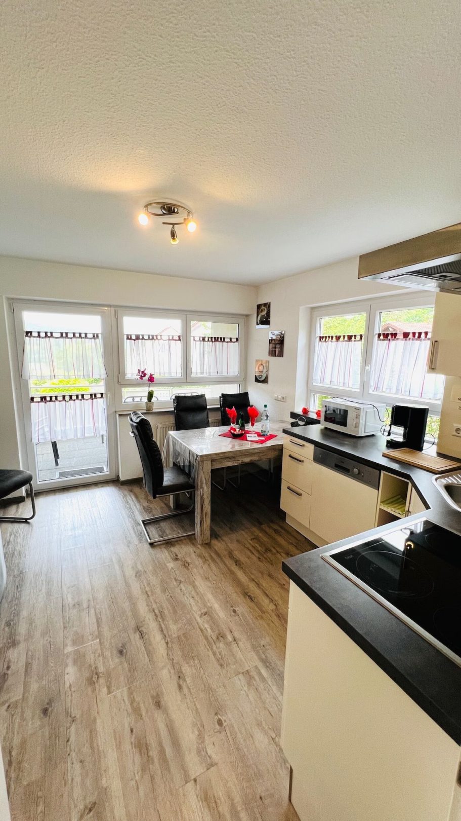 Moderne Küche mit Tisch, Stühlen und großen Fenstern für viel Tageslicht.