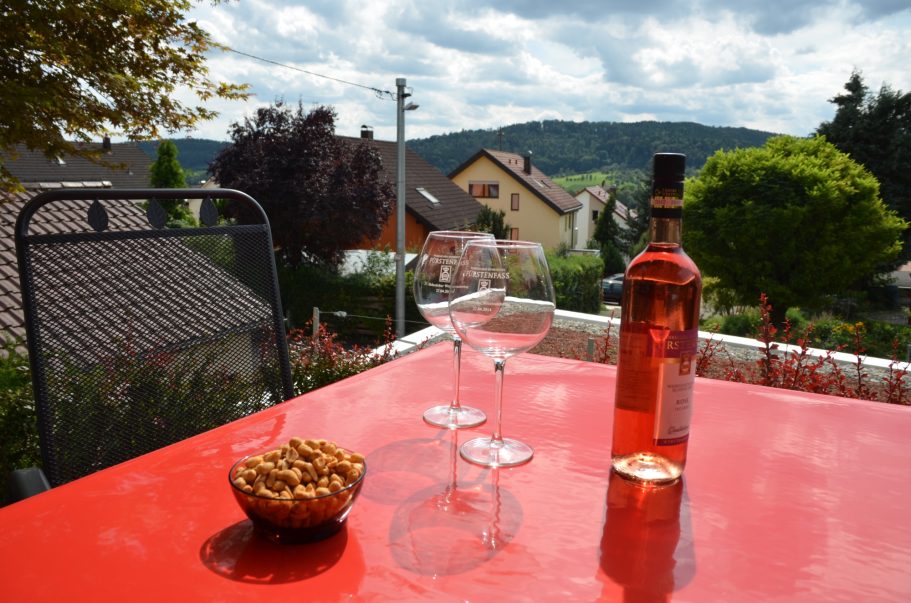 Ein Tisch mit zwei Weingläsern, einer Flasche Rosé und einer Schüssel Nüssen, Blick auf die Landschaft.